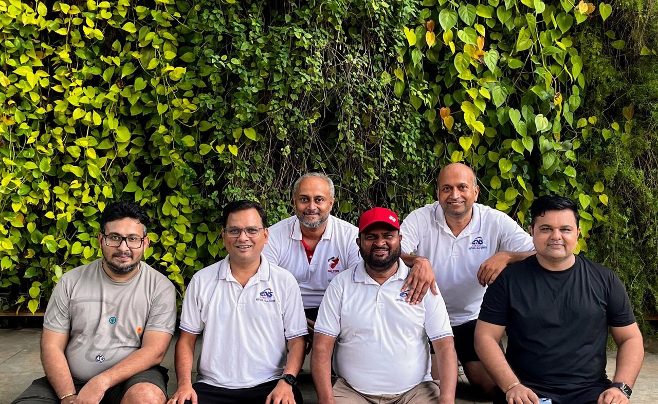 A group portrait of the Shwas Foundation team against a green leafy backdrop